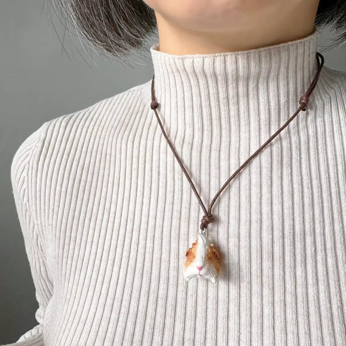 Hand-painted resin pendant of orange & white Abyssinian guinea pig on cotton cord wearing